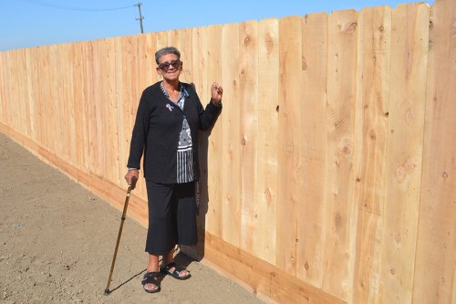 Lemoore's Connie Ford stands proudly next to her new fence, built the day before by a consortium of Navy volunteers and local residents.
